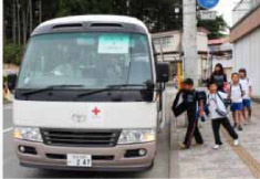 子供たちの笑顔と安全を運びます。仮設住宅と学校を結ぶスクールバスイメージ